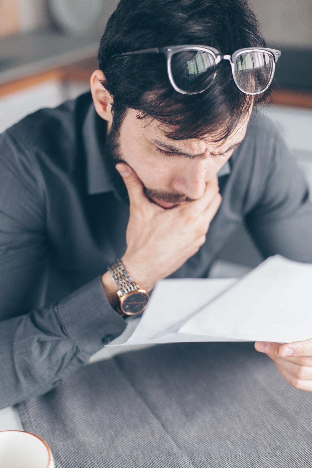 photo of man with hand on chin looking at papers deciding between debt settlement or filing for bankruptcy
